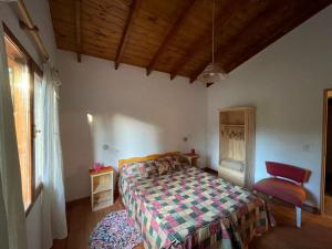 Un dormitorio con una cama y una silla y una ventana. en Ranel Bolsón, en El Bolsón