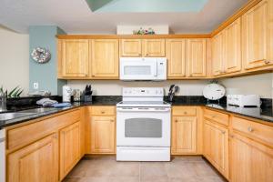 格尔夫海岸Crystal Shores West 807 condo的厨房配有木制橱柜和白色炉灶烤箱。