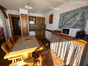 a kitchen with a wooden table and a microwave at Location Appartement - Le grand Bornand Chinaillon - Pied des pistes in Le Chinaillon