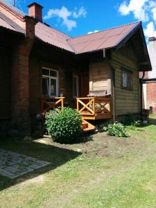 a log cabin with a porch and a porch swing at Viesu Nams Vilhelmīne in Līgatne