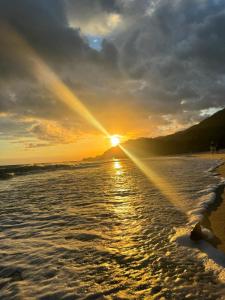 a sunset on a beach with the sun setting at Pousada Barra do Sahy in Barra do Sahy