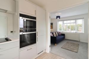 a kitchen with white cabinets and a living room at Round House view in Brimington +13 photos