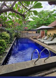 a swimming pool with blue water in a yard at Petit Boo Amed in Amed