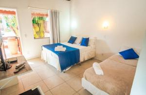 a hotel room with two beds and a couch at Pousada Iwalu in Búzios