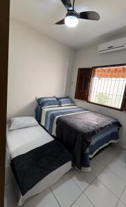 a bedroom with two beds and a ceiling fan at Casa de Praia Encanto Tamandaré - A 300m das Piscinas Naturais in Tamandaré