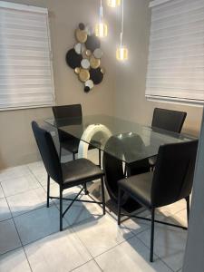 a dining room with a glass table and black chairs at Dreamscape in Fajardo