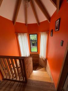 an orange room with a staircase and a window at Cabañas Estacion del Lago in Puerto Varas