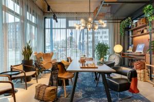 a room with a table and chairs and windows at Moxy Berlin Ostbahnhof in Berlin