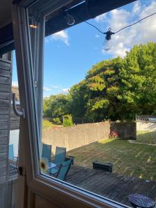 a window with a view of a yard with two chairs at Charmante maison en pierre, avec terrasse et jardin privé in Jallais