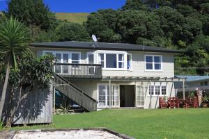 a white house with a balcony and a yard at KBHH - Beachfront Paradise - BUR1 in Ohope Beach