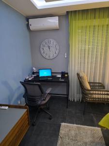 an office with a desk with a laptop and a clock at Pretty Modest Apartment in Prizren