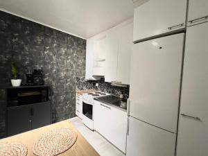 a kitchen with white cabinets and a white refrigerator at Helmi Villa, keskellä Vuokatti Sauna Ilmainen Pysäköinti Wi-Fi in Vuokatti