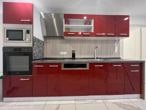 a kitchen with red cabinets and a microwave at Haus am Park Dreieich in Dreieich