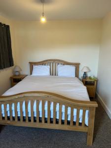 a bedroom with a wooden bed with two pillows at 3 Green Cloth in Hackington
