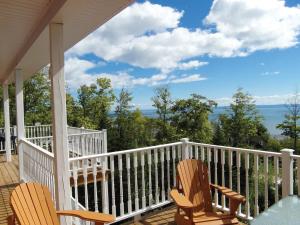 a porch with two chairs and a view of the water at Chalet L'Officier #1 et #2 Charlevoix in Petite-Rivière-Saint-François