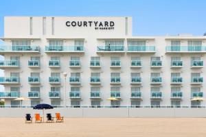 ein Hotel am Strand mit Stühlen und einem Sonnenschirm in der Unterkunft Courtyard by Marriott Ocean City Oceanfront in Ocean City + 55 Fotos