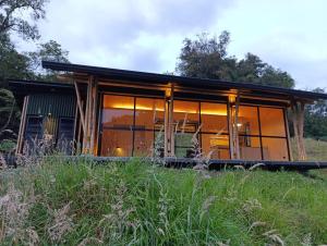 马尼萨莱斯Glamping Bosque de helechos, privacidad y cercanía的田野上设有大型玻璃窗的房子