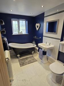 a blue bathroom with a tub and a sink at 5 Bed Cottage Free Parking in Stainforth