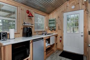 a kitchen with wooden walls and a white door at Pixie's Porch Tiny Home in Centerville