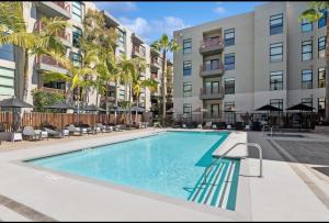 a swimming pool in front of a building with palm trees at 1BR in Hollywood w patio & parking!! in Los Angeles