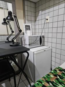 a kitchen with a table and two lamps on a refrigerator at Quarto Capsula 1 207 in Brasília