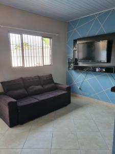 a living room with a couch and a flat screen tv at Beach house in Peruíbe in Peruíbe