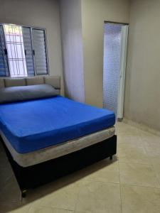 a bedroom with a blue bed and a shower at Beach house in Peruíbe in Peruíbe