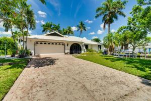 a house with a driveway and palm trees at Canal-Front Gem with Lanai and Dock in Cape Coral in Cape Coral Hospital Heliport