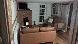 a living room with a couch and a fireplace at Magpie Cottage in Ledbury
