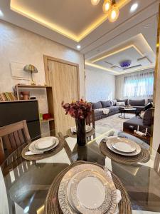 a living room with a glass table with plates on it at Chic & Cozy Apartment in Tangier in Oulad Akkou