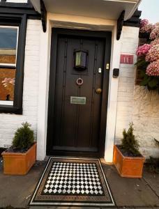 a black door of a house with potted plants at Romantic Boutique Cottage with pink roll-top bath-Hastings Old Town in Hastings +16 photos