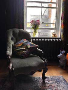 a chair with a pillow in a room with a window at Romantic Boutique Cottage with pink roll-top bath-Hastings Old Town in Hastings