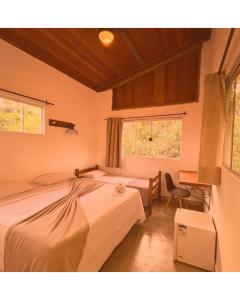 a bedroom with two beds and a desk and two windows at Pousada Aurora da Chapada in Lençóis