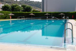 a large swimming pool with blue water and umbrellas at Bungalows Los Álamos de El Pedroso in El Pedroso