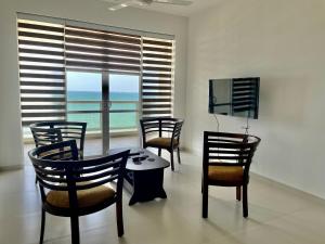 a dining room with chairs and a table and a television at Beachfront Two Bedroom Apartment near Colombo area in Pulluhena