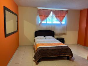 a bedroom with a bed with a window and a mirror at Hostal Villa Franca in Ibarra