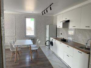 a kitchen with white cabinets and a table and chairs at Akkent 88 Apartment 3 Rooms in Almaty