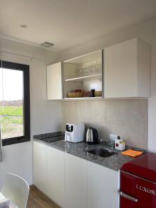 a kitchen with white cabinets and a sink and a window at Eco Lodge - Campos de artaza in Belén