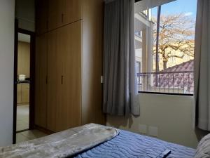 a bedroom with a bed and a large window at Vila Del Rei - Flat no Centro de São João Del rei in São João del Rei