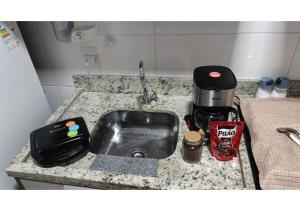 eine Küchentheke mit Spüle und Kaffeemaschine in der Unterkunft Studio Nossa Senhora Aparecida - Condominium of Faith in Cachoeira Paulista + 20 Fotos