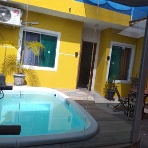 ポンタウ・ド・パラナにあるCasa Shangri-la Ar-Condicionado Piscina TV a cabo Wifi 360mbの黄色い家の前のスイミングプール