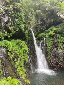 a waterfall on the side of a mountain with water at 森のうた Morinouta Forest Stay in Nikko in Nikko