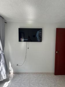 ボゴタにあるGolden Airport Connection Hotelの白い壁の客室で、薄型テレビが備わります。