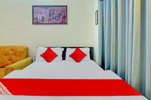 a bedroom with a bed with red pillows and a chair at Super Hotel O New View in Bankipur