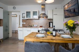 a kitchen with a wooden table with wine glasses and flowers at FeWo Hafenliebe - Kamin, Sauna, Meerblick in Sassnitz