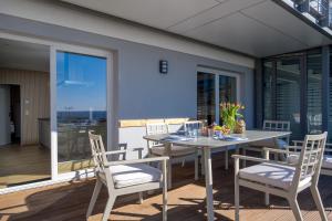 a dining table and chairs on a deck with glass doors at FeWo Silbermöwe - Meerblick,Terrasse, Sauna, Fitness in Sassnitz