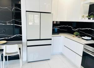 a white kitchen with black and white cabinets and a table at Palm Breeze Getaway in Hollywood
