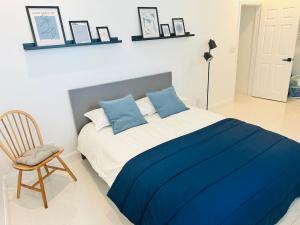 a bedroom with a bed with blue pillows and a chair at Palm Breeze Getaway in Hollywood +8 photos