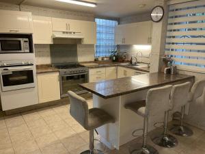 a kitchen with white cabinets and a counter with bar stools at Villa Providencia in Guadalajara