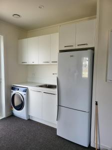 Il comprend une cuisine équipée d'un réfrigérateur blanc et d'un lave-linge. dans l'établissement Seacrest, à Ohakana Island